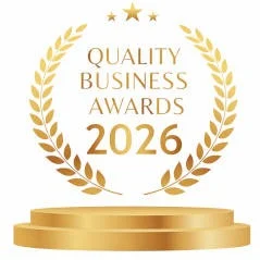 Quality Business Awards 2026 emblem on a gold pedestal.