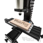 Rat Rig Mill CNC machine carving "RatRig" into wood. Black and silver metal construction, precision machining.