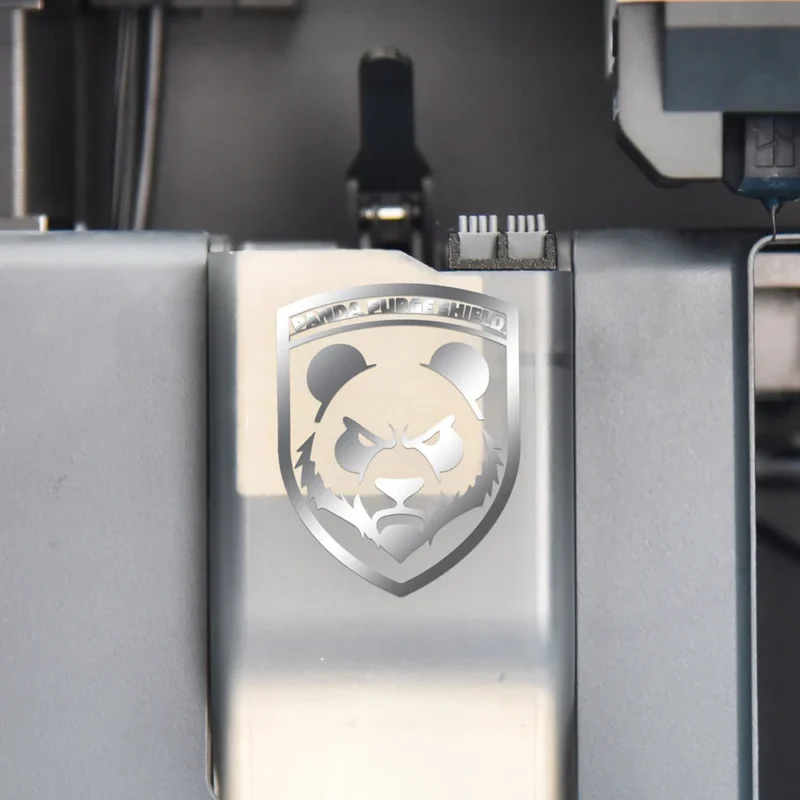 1060000791-PandaPurgeShield_1000_4 Panda Brush PX Panda Purge Shield Nozzle Wiper: Silver metal product with a Panda logo, a nozzle wiper for 3D printers.