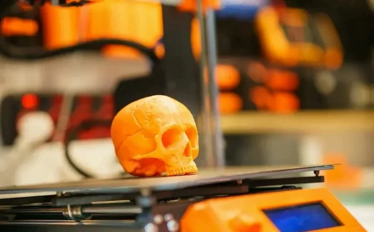 3D-printed orange skull being created by a 3D printer.