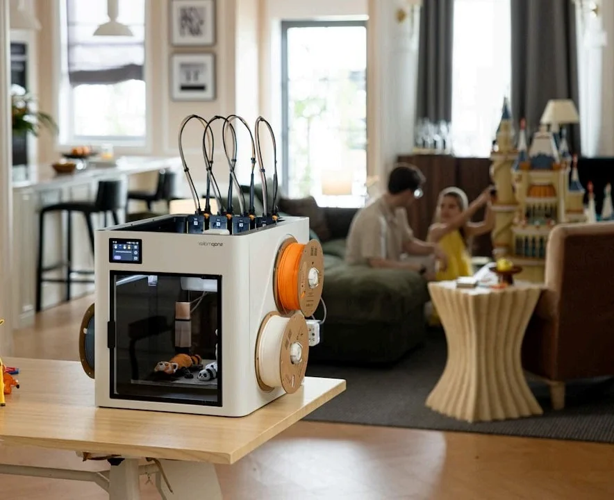 A 3D printer in a home environment, with filament spools attached.