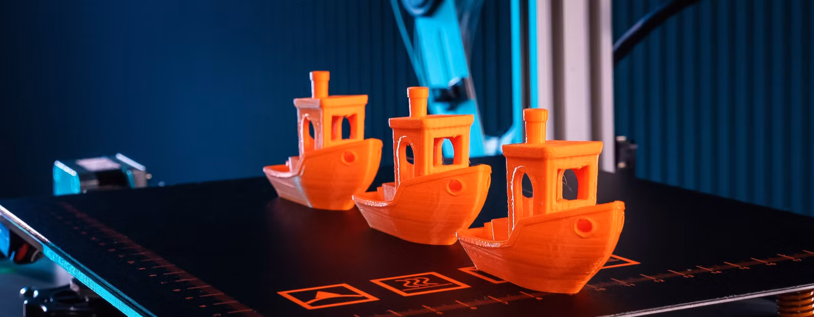 3D printer creating orange Benchy models, illustrating 3D printing costs in Australia.